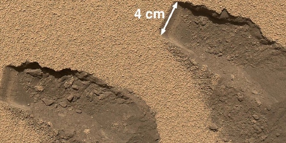Sporen van de arm van Curiosity die bodemstalen neemt van het Marsoppervlak